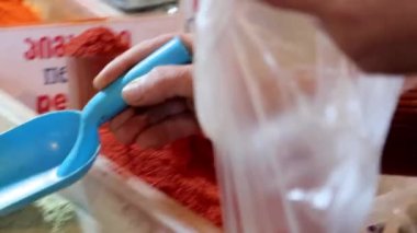 Satıcı torbaya baharat koyar, yakın plan. Baharat almak, piyasa konseptinde baharat, 4K. İngilizce, Gürcüce ve Rusça harflerle yazılmış baharatların adı.