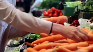 Havuç seçen bir kadın, yakın plan eller. Marketten havuç almak, süpermarkette sebze almak..