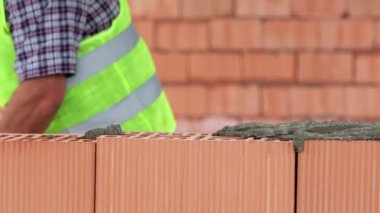 Tuğlacı inşaat tuğlaları döşer. Mason tuğlalara çimento harcı koyar..