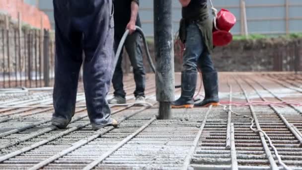 認識できない労働者のグループによって建設現場でコンクリートポンプで基礎を埋める — ストック動画