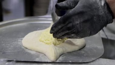 Aşçıya yakın çekim Adjarian 'da khachapuri hazırlar, hamur teknesini peynirle doldurur, süzme peynir. Ulusal Gürcü yemekleri.