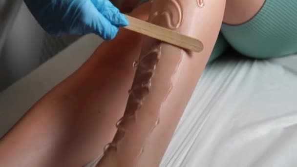 기술자는 머리를 제거하기 레이저 Epilator를 사용하기 스틱을 여자의 다리에 적용합니다 — 비디오