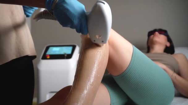 클리닉에서 그녀의 다리에 레이저 제거를 기술자는 휴대용 레이저 장치를 사용하여 — 비디오