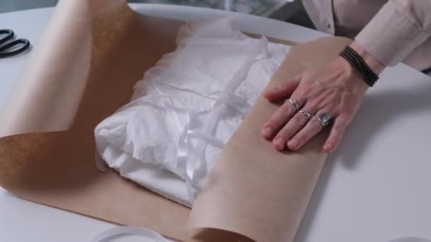 Les mains de la femme, emballer des choses avec du papier éco artisanal pour donner un cadeau. Esthétique close-up vidéo 4k.