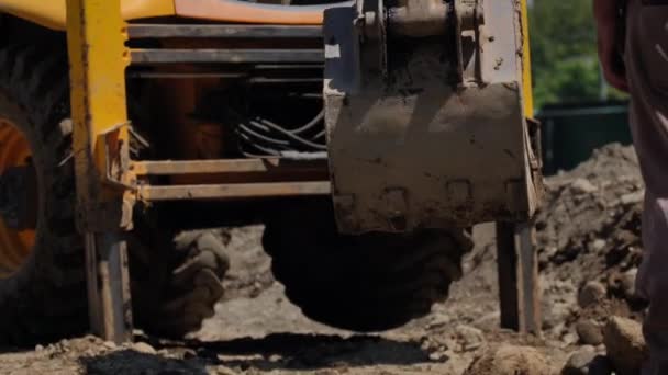掘削機は 忙しい建設現場で土の山を通って落下し 地球を動かす操作の精度を示しています — ストック動画
