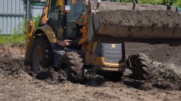 建設現場に陸地を運搬する黄色い掘削機は 重機の動作能力を示しています — ストック動画