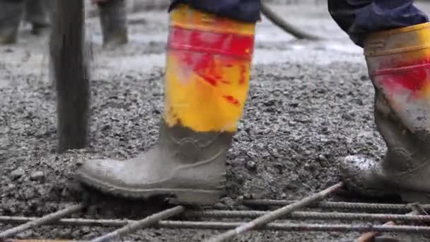 建設現場の閉鎖 建物の基礎にコンクリートを注ぐ労働者の汚れたゴム製ブーツ — ストック動画