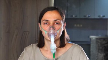 Kameraya bakan genç bir kadın zatürree sırasında evde solunum tedavisi için nebulizatörle ilaç soluyor..