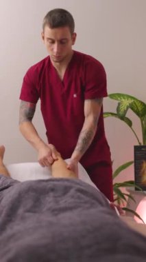 Profesyonel fizyoterapist bir hastaya terapi amaçlı ayak masajı yapıyor. Uzman masaj terapisi ayak rahatlığı ve sağlığa odaklandı. Dikey görüntüler.