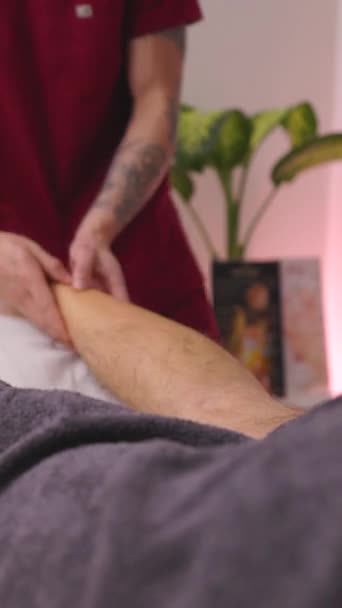 男性治疗师为男性提供有针对性的运动腿按摩 采用按摩技术放松和肌肉舒缓 垂直镜头 — 图库视频影像
