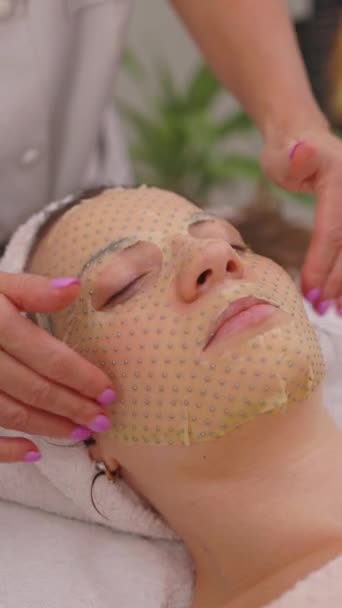 Kozmetik Uzmanı Hastanın Yüzünde Çarşaf Maskesiyle Yüz Masajı Yapıyor Kozmetoloji — Stok video