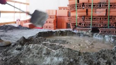 Tanınmayan inşaat işçisi inşaat alanında bir kürek kullanarak çimentoyu kumla karıştırıyor. İnşaat amaçları için çimento oluşturma süreci yakın plan.