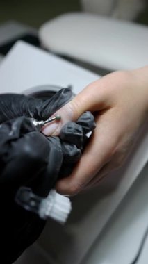 Dikey video biçiminde hijyenik donanım manikürü, tırnak içi düzeltmeye odaklanma, yakın çekim.