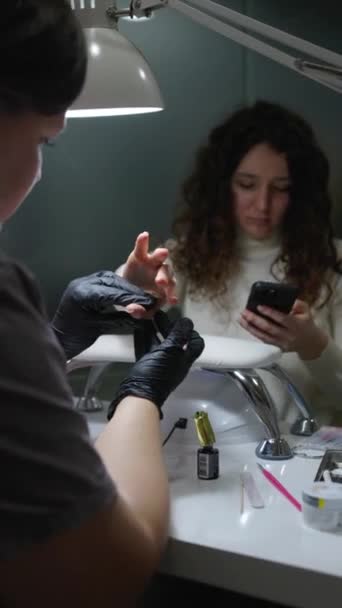 Genç Bir Kadın Akıllı Telefonunu Kullanırken Kuaförde Manikür Yaptırıyor Dikey — Stok video