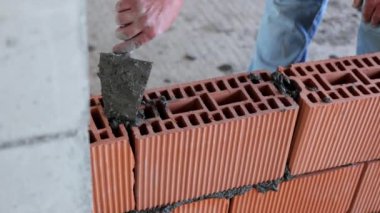 İnşaat işçisi kırmızı tuğlaya beton döşüyordu. İnşaat alanı, tuğla döşeme, yakın plan..