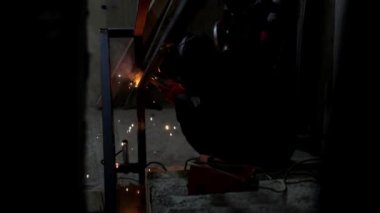 İşçiler, karanlık odada yavaş çekimde bir inşaat alanında korkuluk inşa ederken kaynak işlemi....