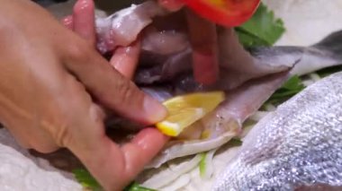 Limon, domates, soğan ve maydanozla dolu, lezzetli bir yemek için mükemmel pişirilmeye hazır kesilmiş bir balık. Doldurulmuş balık hazırlığı, Dorado..