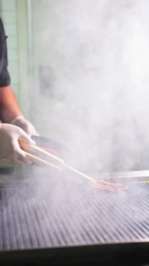 Şef, restoranın mutfağındaki ızgaraya ahtapot koyuyor..