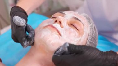 Lüks bir kaplıcada güzel bir kadın hastaya yüz masajı yapan bir doktor. Güzellik tedavisi, sağlıklı cilt için yenilenme maskesi ve detoks terapisi içeriyor..