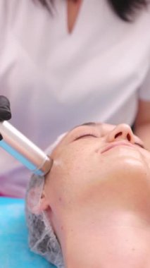 Güzellik uzmanı bir kozmetik uzmanı gelişmiş donanım kozmetik teknikleri kullanarak yüz derisi soyma prosedürü uyguluyor. Dikey çekim, yakın plan..