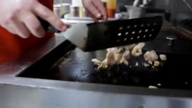 Fast food restoranındaki bir aşçı fırında et kızartıyor. Yemek pişirme teknikleri ve yemek hazırlama sahneleri için mükemmel..