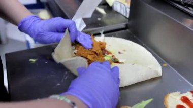 Bir şef ızgara tavukla pişirirken çabucak ve profesyonelce bir burrito ve shawarma sarar. Fast food hazırlama ve aşçılık becerilerini sergilemek için ideal..
