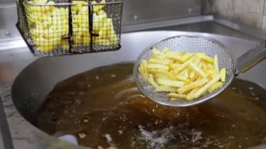 Patates kızartması kaynayan yağdan bir kazanda kızartılır, yakın planda yakalanır. Restoran mutfağında ya da kafe ortamında kızartma pişirme sürecini sergilemek için mükemmel..