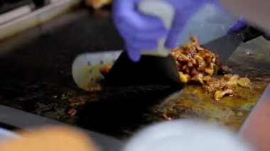 Bir aşçının, sosta kıyma ve baharatları profesyonel bir fırında kızartıp karışımı karıştırdığı yakın plan bir fotoğraf..
