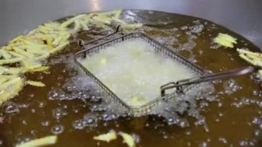 Fast food restoranında patates kızartması yapmak için bir fıçı kızgın yağda kızartılır. Yavaş çekim, kızartma işlemini yakalar, fast food hazırlar..