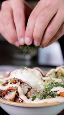 Bir şefin elleri yakın plan çekimde bir Japon dürtme çanağının üzerine doğranmış Norveç yosunu serer. Dikey video biçimi, yemek hazırlama, yemek pişirme ve tarif içeriği için mükemmel.