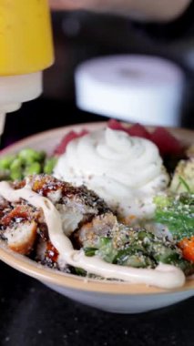 Japon yemeği pişirme süreci, dürtme. Aşçı bitmiş tabağın üzerine sos döküyor, eller yakın çekim, dikey video biçimi.