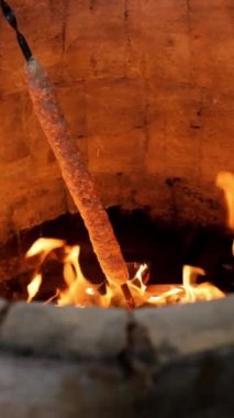 Bir aşçı, açık ateşte kıymalı et kebabı kızartır. Dikey ağır çekim video, ızgara, et hazırlama ve pişirme içeriği için ideal.