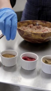 Bir şefin elleri kıymaya baharat döker ve ahşap bir kasede iyice karıştırır. Yakın çekim, yemek pişirmek ve yemek hazırlamak için mükemmel.