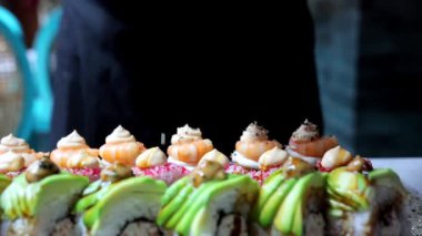 Yavaş çekimde üzerine susam tohumları serpiştirilmiş bir suşi. Yemek sunumu ve suşi yapma teknikleri için mükemmel..