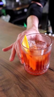 Barmenin elleri barın karşısındaki bardakta buzlu alkollü bir içeceği taşırken. Kokteyl sunumu ve bar servisi için mükemmel, yakın plan..