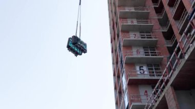 Kablodaki bir vinç çok katlı bir binaya ağır bir yük kaldırır. Bu alttaki görüntü inşaat sürecini gösteriyor. İnşaat, vinç ve inşaat projeleriyle ilgili videolar için mükemmel..