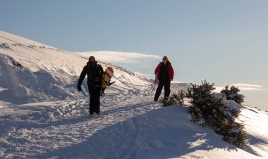 Edinburgh, Scotland; 02/11/2021: Woman and man holding a snowboard walking on the snow at the Pentland Hills on a sunny day clipart