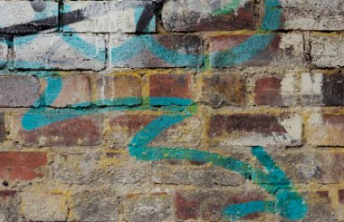 Üzerinde mavi bir okun grafitisi olan eski bir kırmızı tuğla duvarın arkaplan resmi. Kentsel
