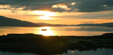 Pulpit Hill, Oban 'dan deniz üzerinde gün batımı. İskoçya 'nın batı kıyısı. Kerrera Adası ön planda ve Mull Adası 'ndan feribot arka planda. Argyll ve Bute