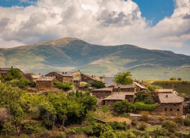Roblelacasa, İspanya 'nın Guadalajara kentindeki küçük bir kırsal köy, yeşil ağaçlar ve Ocejon dağının arka planında ve mavi gökyüzünde bulutlarla çevrili taş ve siyah tahta evlerle çevrili. Mimari Sierra Norte de Guadalajara