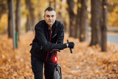 Güz parkında bisikletli genç, güzel atletik bir adam..