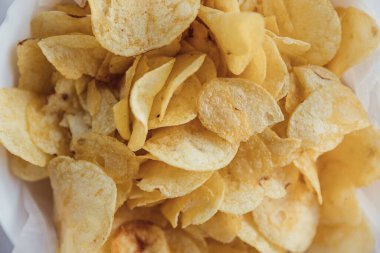 Eski mutfak masasında bir hasır kase gevrek patates cipsi