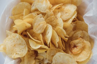 Eski mutfak masasında bir hasır kase gevrek patates cipsi