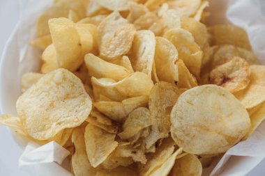 Eski mutfak masasında bir hasır kase gevrek patates cipsi