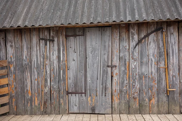doors or barn doors made of planks that can be pulled to the side along a skid rail. the door hangs on a hinge with wheels. retractable shutters made of wood on the cottage