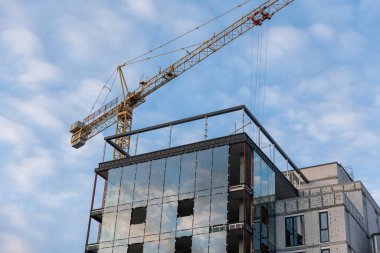Roofer works on the roof structure of a building at a construction site. Roofer uses an air gun or air gun and install Metal Sheet on a new roof in Asia.