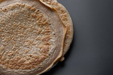 Üzerinde taze muz, ceviz ve bal dilimleri olan bir yığın yulaf ezmeli gözleme ve beyaz ahşap arka planda bir fincan çay. Sağlıklı bir kahvaltı. Boşluğu kopyala