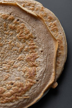 Üzerinde taze muz, ceviz ve bal dilimleri olan bir yığın yulaf ezmeli gözleme ve beyaz ahşap arka planda bir fincan çay. Sağlıklı bir kahvaltı. Boşluğu kopyala