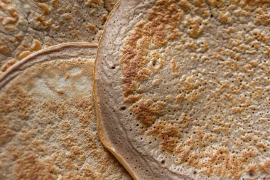 Üzerinde taze muz, ceviz ve bal dilimleri olan bir yığın yulaf ezmeli gözleme ve beyaz ahşap arka planda bir fincan çay. Sağlıklı bir kahvaltı. Boşluğu kopyala