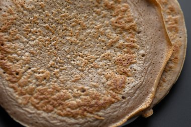 Üzerinde taze muz, ceviz ve bal dilimleri olan bir yığın yulaf ezmeli gözleme ve beyaz ahşap arka planda bir fincan çay. Sağlıklı bir kahvaltı. Boşluğu kopyala